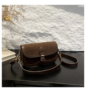 Detail of vintage brown suede crossbody bag showing textured fabric and gold buckle