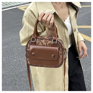 Close-up of vintage brown floral patterned crossbody bag held by a model in a trench coat