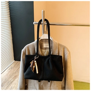 Détail du sac cabas en toile noire avec pendentif en perles de bois et coutures verticales
