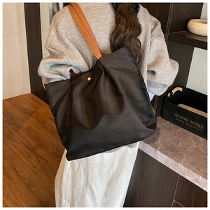Lifestyle shot of large black nylon tote bag with brown leather handles and gold detail