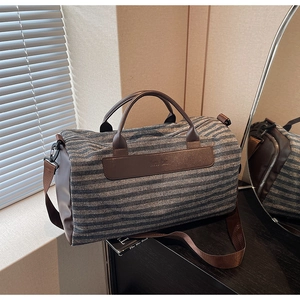 Detail of blue striped canvas gym bag with brown leather handles and adjustable strap