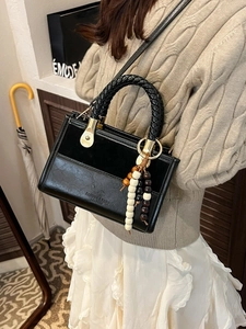 Sac à main chic en cuir noir avec poignée tressée et perles colorées sur modèle