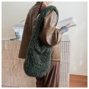 Detail shot of fluffy dark green faux fur tote bag styled with a brown leather jacket