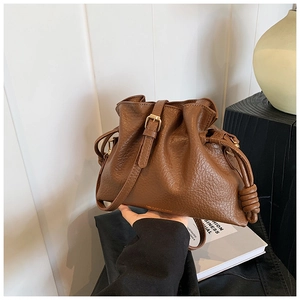 Close-up of deep brown bucket bag with lychee grain texture and gold brand logo details