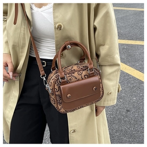 Detail of vintage brown floral crossbody bag with leather handles on a beige trench coat