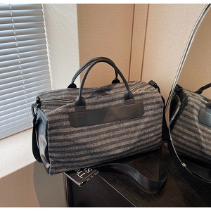 Detail of blue striped sports gym bag with black leather handles and shoulder strap texture