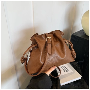 Detailed macro view of the brown drawstring bucket bag with soft lychee leather texture