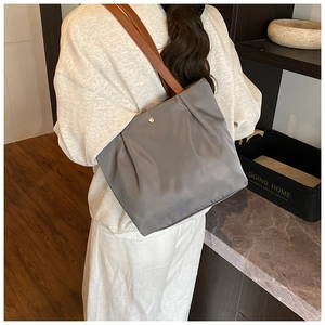 Detail of dark grey tote bag with brown leather strap and elegant gold snap button closure