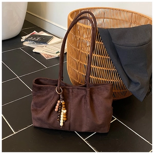 Détail d'un sac cabas en daim marron avec de longues anses et des perles en bois