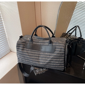 Detail view of striped travel bag with shoe compartment and adjustable shoulder strap
