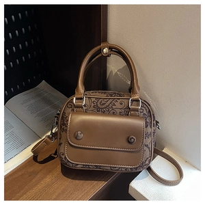 Close-up of brown paisley print texture and magnetic flap on a vintage crossbody bag