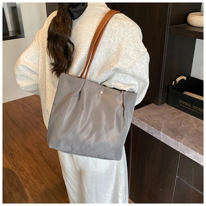 Detail of grey satin tote bag with brown leather straps and pleated metal buckle closure