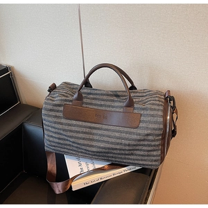 Detail view of the gray striped texture and brown leather handle on this gym bag