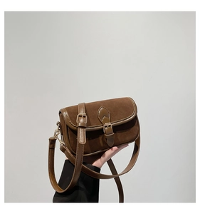 Detail view of vintage dark brown crossbody bag with suede texture and metal buckles