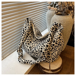 Detail of leopard print tote bag fabric and wide strap near a rustic ceramic vase