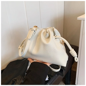 Close-up of cream leather bucket bag showing drawstring closure and golden logo