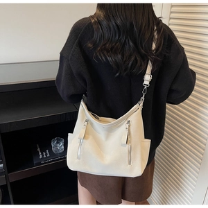 Detail view of large white faux leather tote bag with silver zippers and adjustable strap