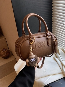 Vintage brown bowling bag with embossed logo and fuzzy monster charm for women