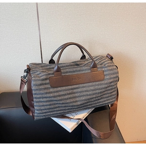 Close-up of striped fitness bag with leather handles and embossed logo on a chair