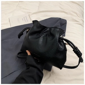 Detail shot of black faux leather bucket bag featuring lychee texture and drawstring closure