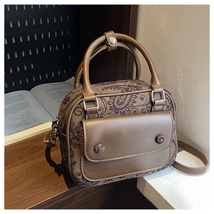 Detailed close-up of retro brown paisley pattern and leather texture on a crossbody bag