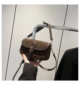 Detail showing deep brown suede texture and vintage buckle on minimalist shoulder bag