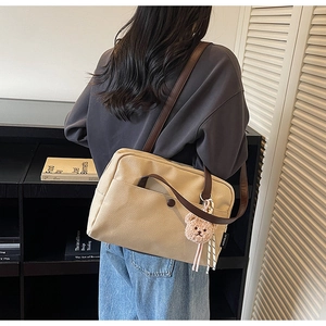 Khaki canvas tote bag detail with brown leather strap and a cute plush bear pendant