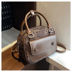 Detail of vintage brown paisley handbag showing the textured front pocket and dual handles