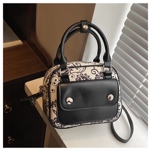 Close-up of vintage canvas and black leather handbag with retro floral patterns