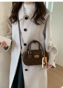 Détail du sac Boston marron en daim synthétique avec perles en bois et logo doré
