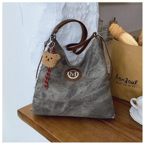 Détail du sac bandoulière en toile vintage avec garniture cuir et breloque ourson