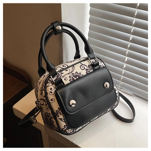Retro floral canvas crossbody bag with black leather handles shown in a lifestyle window setting