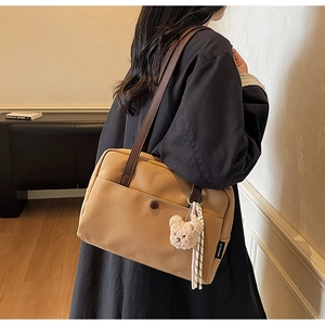 Detail of khaki canvas tote with brown leather straps and cute bear pendant charm