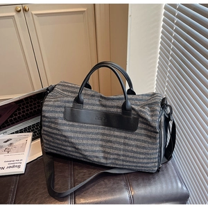 Detailed view of striped travel bag with durable leather handles and branded patch
