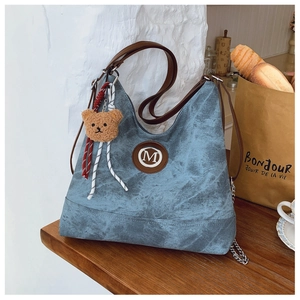 Détail du sac cabas bleu marine avec bandoulière en cuir brun et porte-clé ours