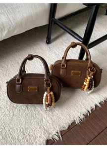 Détail des sacs Boston vintage en marron foncé et caramel avec des breloques perlées