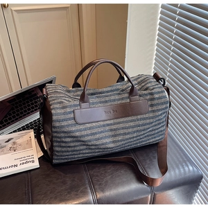 Detail view of striped fabric travel bag with shoe compartment on a leather bench