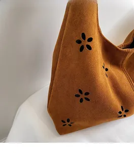 Détail du sac bandoulière en daim marron avec motifs floraux ajourés au laser