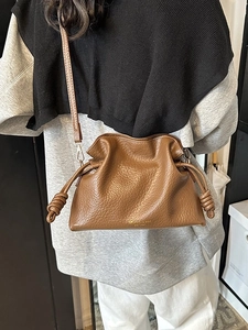 Brown lychee leather bucket bag with drawstring knot details and cloud-pleated design