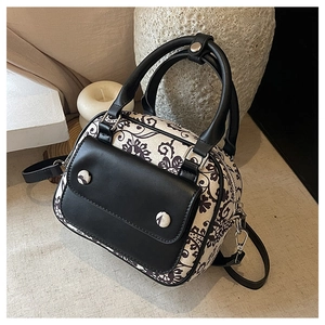 Detail of floral knit crossbody bag with dual handles on a minimalist fabric surface