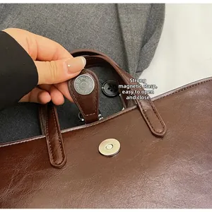 Detail of strong magnetic snap closure on vintage brown faux leather bucket bag