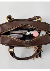 Vue de dessus du sac bandoulière marron montrant l'intérieur spacieux et les essentiels