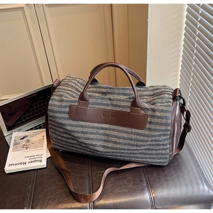 Close-up of the blue striped canvas bag with leather handles and brand logo detail