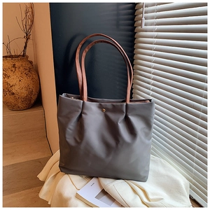 Detail of grey nylon tote bag showing textured waterproof fabric and brown leather strap