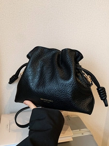 Fashionable black ruched leather bucket bag with gold lettering and drawstring closure