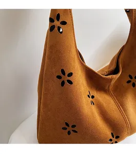 Gros plan sur un sac cabas en daim marron avec des motifs floraux ajourés élégants
