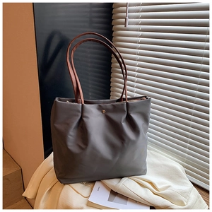 Detail of grey tote bag showing smooth matte texture and premium leather handles