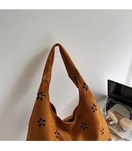 Détail du motif floral découpé au laser sur sac hobo en daim marron à large bandoulière