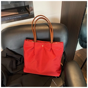 Detailed shot of a red nylon tote bag with leather handles on a black office chair