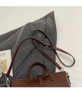 Detail of brown leather handbag featuring silver hardware and adjustable shoulder strap